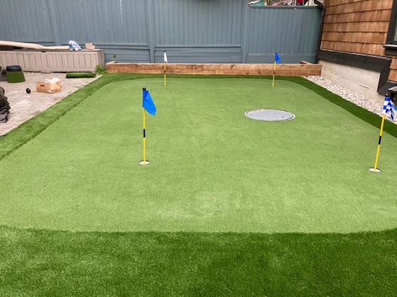 Private backyard putting green with artificial turf and flagsticks