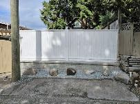 White vinyl fence on a block retaining wall with gravel and boulder accents